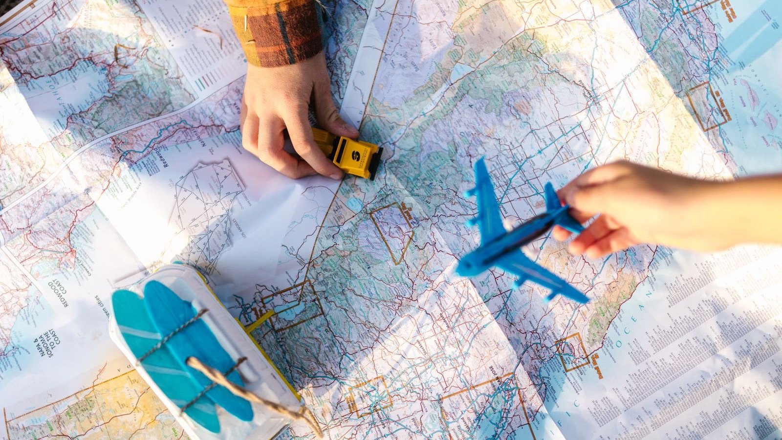 Hands moving a toy car and plane across a paper road map